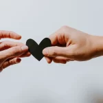 Two hands holding black paper heart to illustrate text