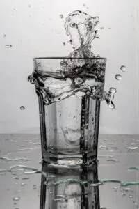 Image of glass of water on table being splashed on to surface of table to illustrate post