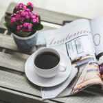 Photo of table with flowers, newspaper and coffee on top to illustrate post.