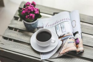 Photo of table with flowers, newspaper and coffee on top to illustrate post.