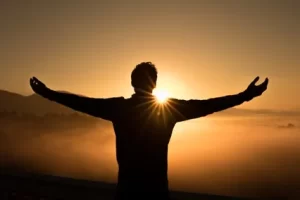 Image of person throwing arms out in celebration of the sun