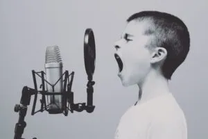 Image of boy forcefully using his voice through a spitguard on to a microphone to illustrate post