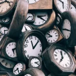 Image of a jumble of old clocks to illustrate post