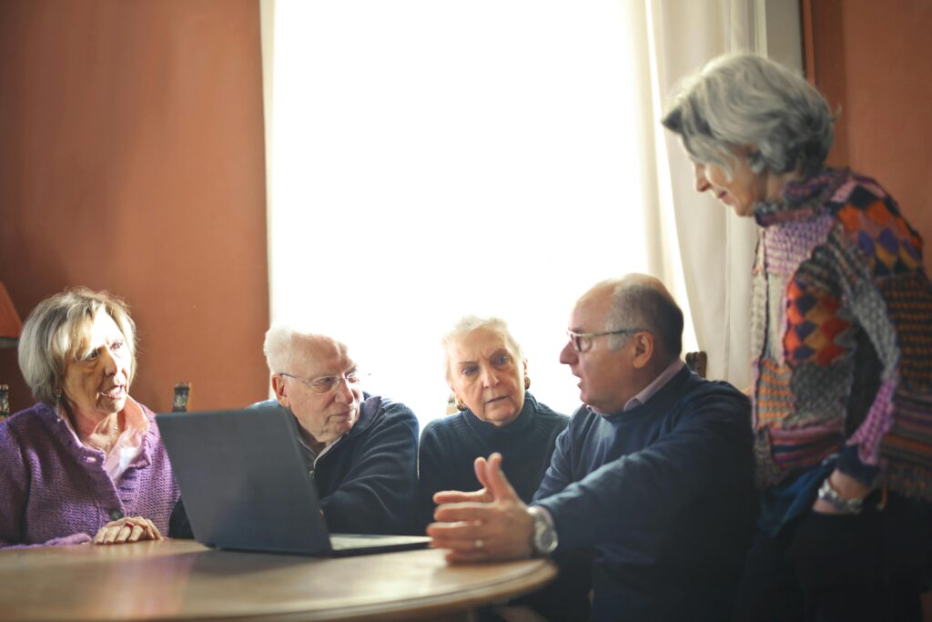 A group of old people looking at a computer and talking together, used to illustrate post.