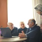 A group of old people looking at a computer and talking together, used to illustrate post.